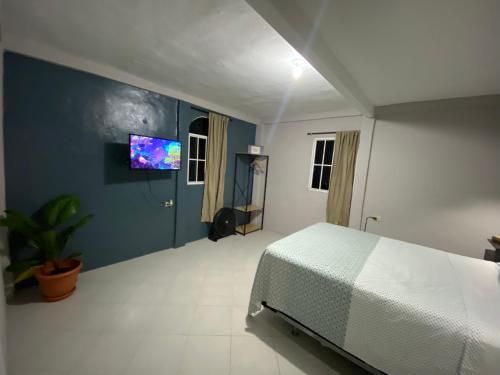 a bedroom with a bed and a tv on the wall at Habitación cerca del aeropuerto #1 