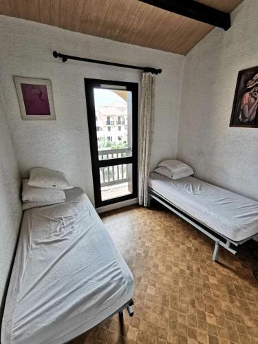 deux lits dans une chambre avec une fenêtre dans l'établissement Résidence Maisons Des Sables 4 - APPT T2 CAB OU MEZZ 6 couchages PORT LEUCATE. Réf: 2MS4_156 MAE-6114, à Port-Leucate