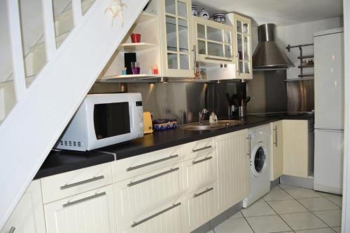 une cuisine avec des armoires blanches et un micro-ondes dans l'établissement Résidence Grande Bleue - VILLA T1 CAB MEZZ 5 couchages PORT LEUCATE MAE-6184, à Port-Leucate