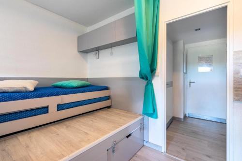 une chambre avec un lit et un rideau bleu dans l'établissement Hyeres Parc - maeva Home - Studio 4 personnes Sélection MAE-6606, à Hyères