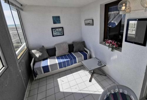 Cette petite chambre comprend un canapé et une fenêtre. dans l'établissement Résidence Copacabana - Appartement deux pièces pour 4 personnes avec très belle vue sur mer. Réf: 1COP_825H MAE-6224, à Port-Leucate