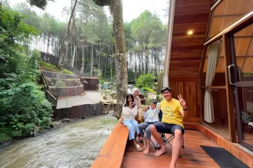 a group of people sitting on the porch of a house at Luxury cabin and cafe hutan pinus rahong in Palayangan