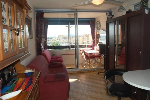 - un salon avec un canapé rouge et une fenêtre dans l'établissement Résidence Karukera - STUDIO 2 PERSONNES 3 couchages PORT LEUCATE MAE-6424, à Port-Leucate