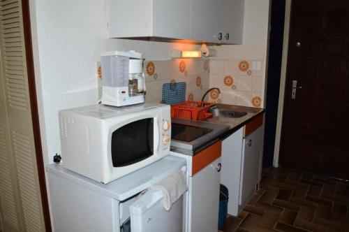 uma pequena cozinha com um micro-ondas e um lavatório em Résidence LES CYCLADES - Studio pour 2 Personnes 54 em Port Leucate