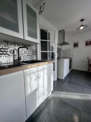 a kitchen with white cabinets and a counter top at Maison confortable - 5min de Carcassonne in Conques-sur-Orbiel