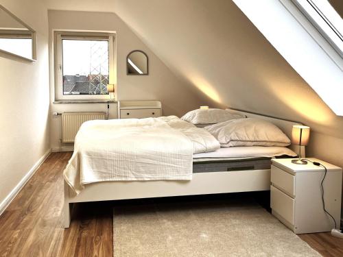 sypialnia z białym łóżkiem na poddaszu w obiekcie Ferienhaus Niwaki w mieście Ratekau