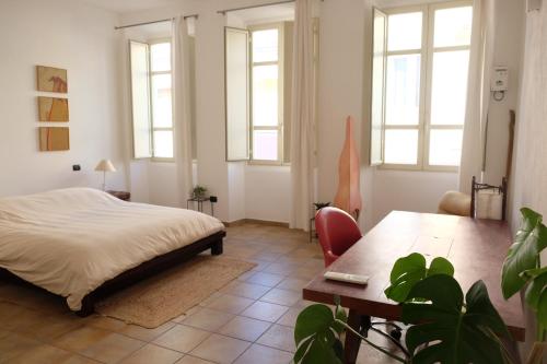 a bedroom with a bed and a table and windows at Casa Marina Guesthouse Cagliari in Cagliari