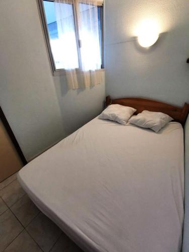 un lit blanc dans une chambre avec une fenêtre dans l'établissement Résidence Copacabana - Appartement deux pièces avec accès direct à la plage à Port Leucate. Réf: 1COP_102A MAE-6494, à Port-Leucate
