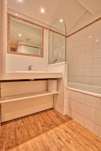 une salle de bain avec un lavabo, une baignoire et un miroir dans l'établissement Résidence Le Village - Appartement 10 personnes au centre du village MAE-2194, à Notre-Dame-de-Bellecombe