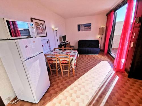 Il comprend une cuisine équipée d'un réfrigérateur blanc et d'une table avec des chaises. dans l'établissement Résidence Marysable - Confortable appartement deux pièces pour 4 personnes à Port Leucate. Réf: 1MAR_101 MAE-6574, à Port-Leucate