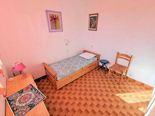 une petite chambre avec un lit et une chaise dans l'établissement Résidence Marysable - Confortable appartement deux pièces pour 4 personnes à Port Leucate. Réf: 1MAR_101 MAE-6574, à Port-Leucate