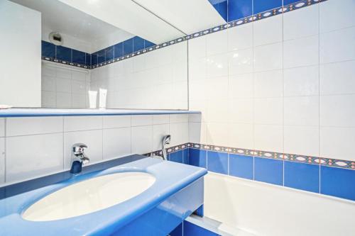 La salle de bains est pourvue d'un lavabo et de carrelage bleu et blanc. dans l'établissement Résidence le Village de Cap Esterel - maeva Home - Appartement 3 pièces 7 personnes - Confort MAE-0548, à Saint-Raphaël
