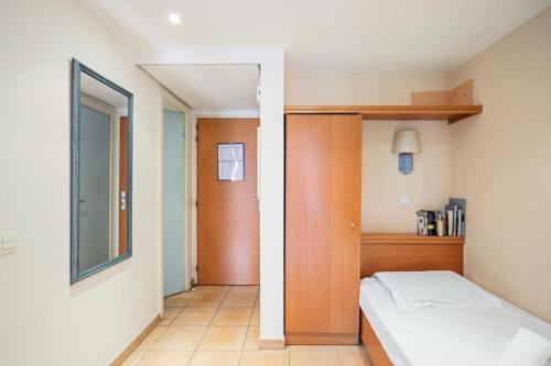 une petite chambre avec un lit et un miroir dans l'établissement Résidence les Rivages du Parc - maeva Home - Studio 5 personnes - Confort MAE-0812, à Menton