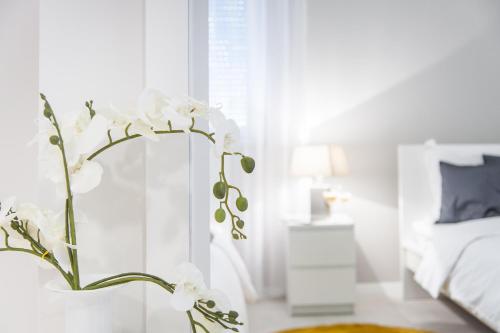 a vase with white flowers in front of a mirror at Apartments Deja Views - Žnjan beach in Split
