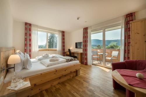 um quarto com uma cama grande e uma varanda em Sontheims Naturhotel & Spa em Maierhöfen