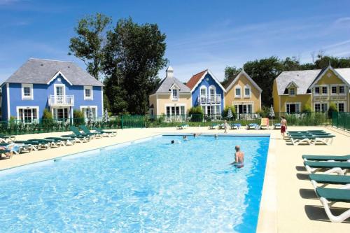 un homme dans une piscine en face des maisons dans l'établissement Les Maisons de Belle Dune - maeva Home - Maison 4 pièces 6 personnes Prestige MAE-2648, à Fort-Mahon-Plage