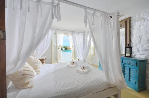 a bedroom with a white bed with two stuffed animals on it at Mykonos Dream Villas in Ftelia