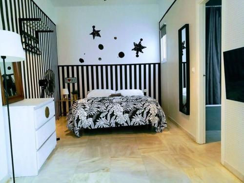 Schlafzimmer mit einem Bett mit einer schwarzen und weißen Bettdecke in der Unterkunft Suite Parking según disponibilidad in Sevilla