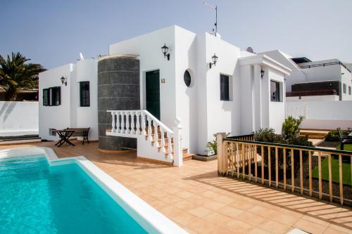 a villa with a swimming pool and a house at Sunny Golf Villas in Puerto del Carmen