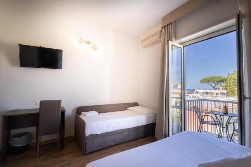 sypialnia z łóżkiem i biurkiem oraz balkon w obiekcie Hotel La Pergola w mieście Sant'Agnello