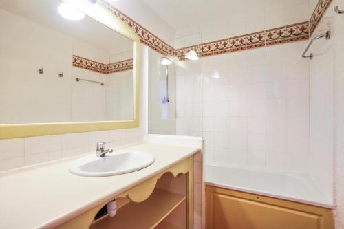 une salle de bain avec un lavabo, une baignoire et un miroir dans l'établissement Les Issambres Lauriers - maeva Home - Appartement 2 pièces 5 personnes Sélection MAE-2988, aux Issambres