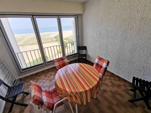 une salle à manger avec une table, des chaises et des fenêtres dans l'établissement Résidence Les Cyclades - 2 Pièces 4 couchages PORT LEUCATE. Réf: 2CYC_120C MAE-6854, à Port-Leucate
