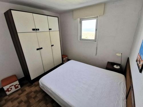 une chambre avec un lit blanc et une fenêtre dans l'établissement Résidence Les Cyclades - 2 Pièces 4 couchages PORT LEUCATE. Réf: 2CYC_120C MAE-6854, à Port-Leucate