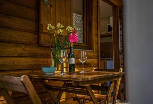 a wooden table with two wine glasses and flowers on it at Chalet 3 étoiles - Piscine - eehig0 in Navarrenx
