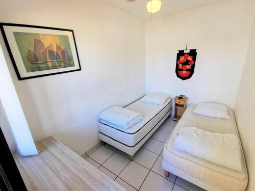 Zimmer mit 2 Betten und einem Bild an der Wand in der Unterkunft Résidence TERRASSES DE LA MEDITERRANEE 1 - 2 Pièces pour 4 Personnes 64 in Port Leucate