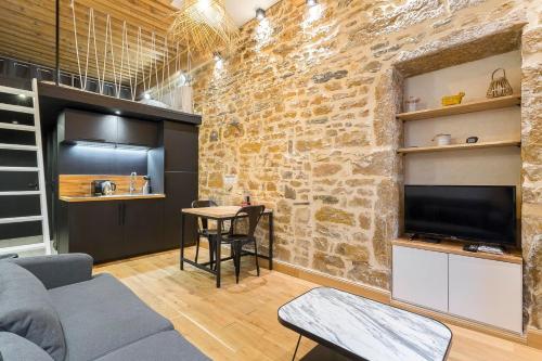 a living room with a stone wall and a tv at Hamac Suites - studio Ainay 1 - hyper centre Lyon in Lyon