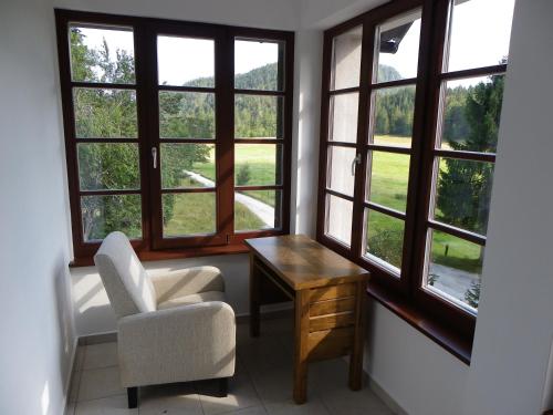 a room with a chair and a table and windows at Triglav Park House in Bled