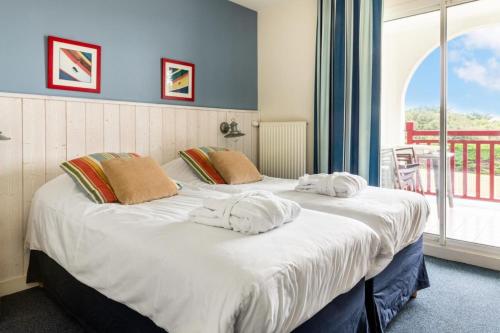deux lits dans une chambre avec une grande fenêtre dans l'établissement Le Domaine De Cramphore - maeva Home - Appartement 2 pièces 4 personnes Confort MAE-5518, au Pouliguen