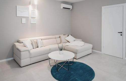 a white living room with a white couch and a table at Apartments Deja Views - Žnjan beach in Split