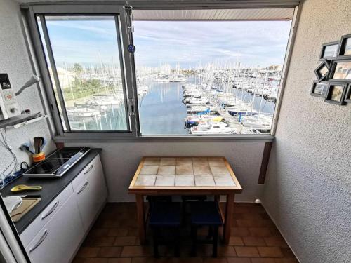 une cuisine avec une fenêtre donnant sur le port de plaisance dans l'établissement Résidence Le Cezelly - 2 Pièces 4 couchages PORT LEUCATE. Réf: 4CEZ_23A MAE-7044, à Port-Leucate