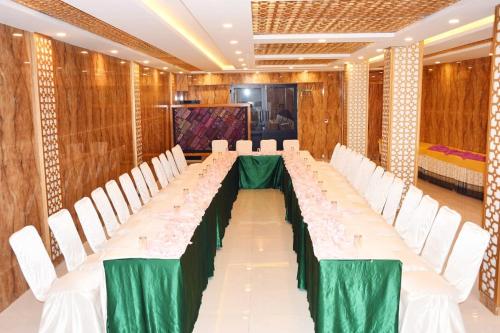 un largo salón de banquetes con sillas blancas y una mesa larga en Swat Continental Hotel, en Mingora