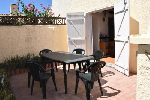 une table noire et des chaises sur une terrasse dans l'établissement Résidence Les Leucatines 1 - VILLA T2 MEZZANINE 6 couchages PORT LEUCATE MAE-7184, à Port-Leucate