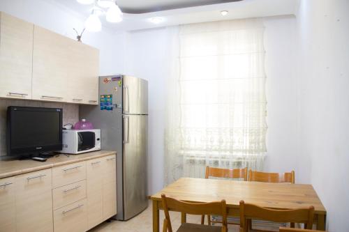 a kitchen with a wooden table and a refrigerator at Apple tree in Almaty