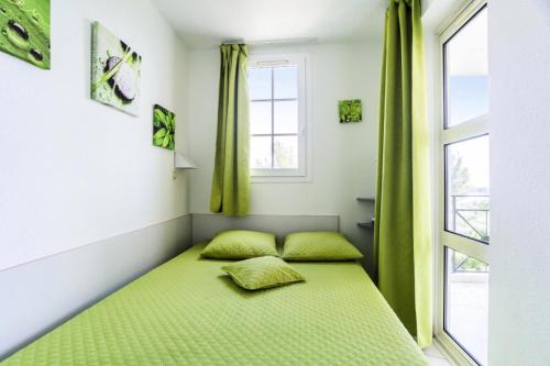 Ce lit se trouve dans un dortoir doté de rideaux verts et d'une fenêtre. dans l'établissement Résidence le Village de Cap Esterel - maeva Home - Appartement 2 pièces 5 personnes - Sélection MAE-7252, à Saint-Raphaël