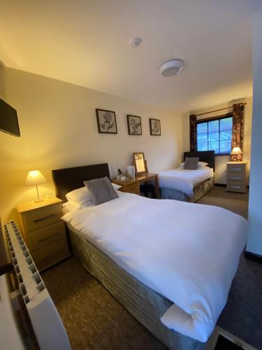 a bedroom with two beds and a desk and a window at Castle Inn in Knighton