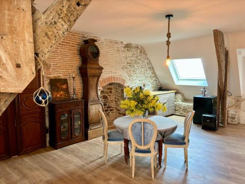 een eetkamer met een tafel en stoelen en een bakstenen muur bij Château de la Pervenchère gîte Marin in Casson