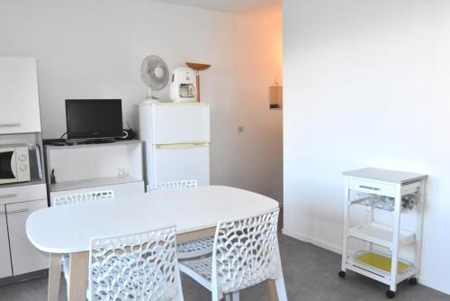 Il comprend une cuisine équipée d'une table blanche et d'un réfrigérateur blanc. dans l'établissement Résidence PORTES DE LA PLAGE 2 - 2 Pièces pour 4 Personnes 54, à Port-Leucate