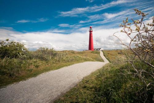 a red lighthouse on a hill with a dirt road at Tiny house - optioneel met hottub in Dokkum