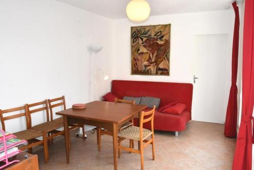 sala de estar con mesa y sofá rojo en Résidence LES CANDEILLERES - Maisons & Villas pour 6 Personnes 94, en Port Leucate