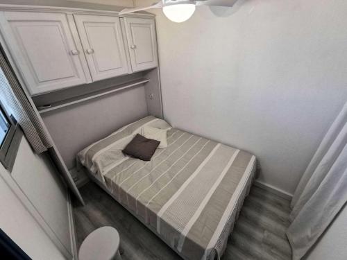 - un petit lit dans une petite chambre avec des armoires blanches dans l'établissement Résidence Copacabana - Magnifique appartement rénové pour 4 personnes à Port Leucate. Réf: 1COP_811H MAE-6944, à Port-Leucate