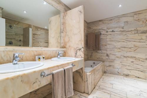 un bagno con 2 lavandini e una vasca di Palm Oasis Maspalomas a Maspalomas