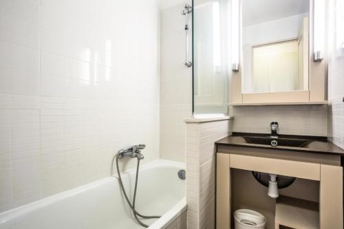 une salle de bain blanche avec un lavabo et une baignoire dans l'établissement Résidence Les Parcs de Grimaud - maeva Home - Appartement 2 Pièces 5 Personnes - Confort MAE-0275, à Grimaud