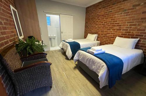 a room with two beds and a brick wall at Village Lodge Harrismith in Harrismith