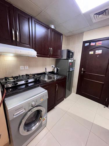 a kitchen with a washing machine and a stove at Fully furnished studio apartment in Ajman 