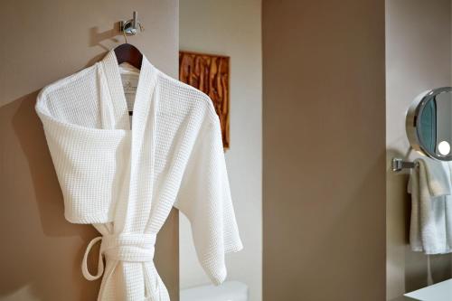 a white robe hanging on a rack in a bathroom at Le Merigot Santa Monica in Los Angeles