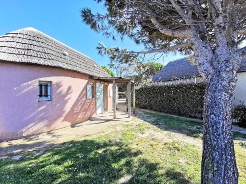 un pequeño edificio rosa con un árbol al lado en Résidence Ile Des Pecheurs - Maisons & Villas pour 6 Personnes 114, en Port Leucate